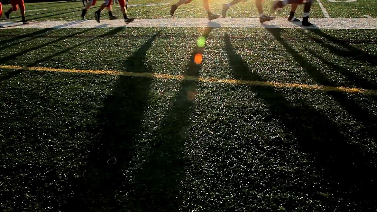 field sideline with athletes running - Homepage